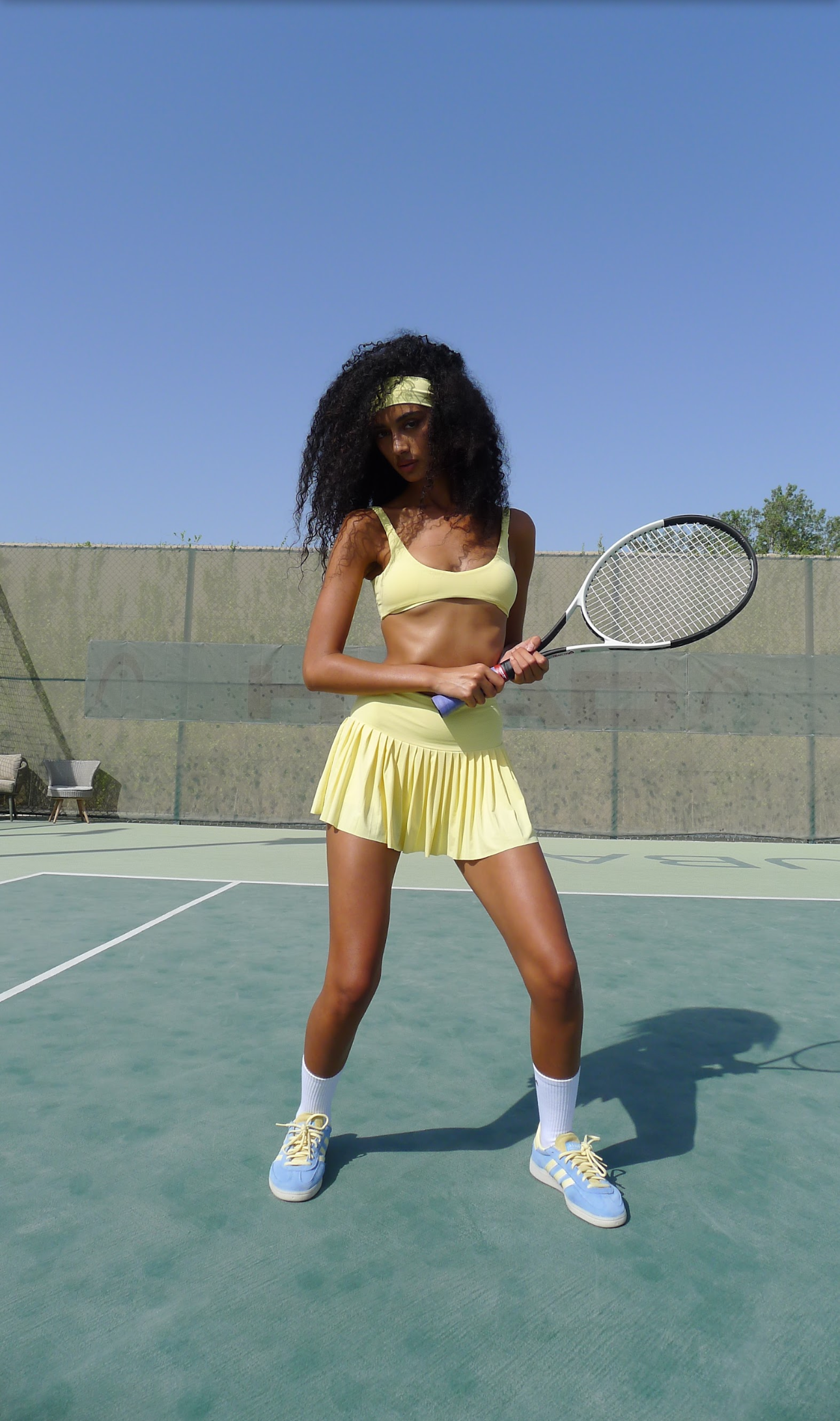Woman in yellow tennis outfit holding a racket on a tennis court