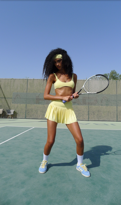 Woman in yellow tennis outfit holding a racket on a tennis court