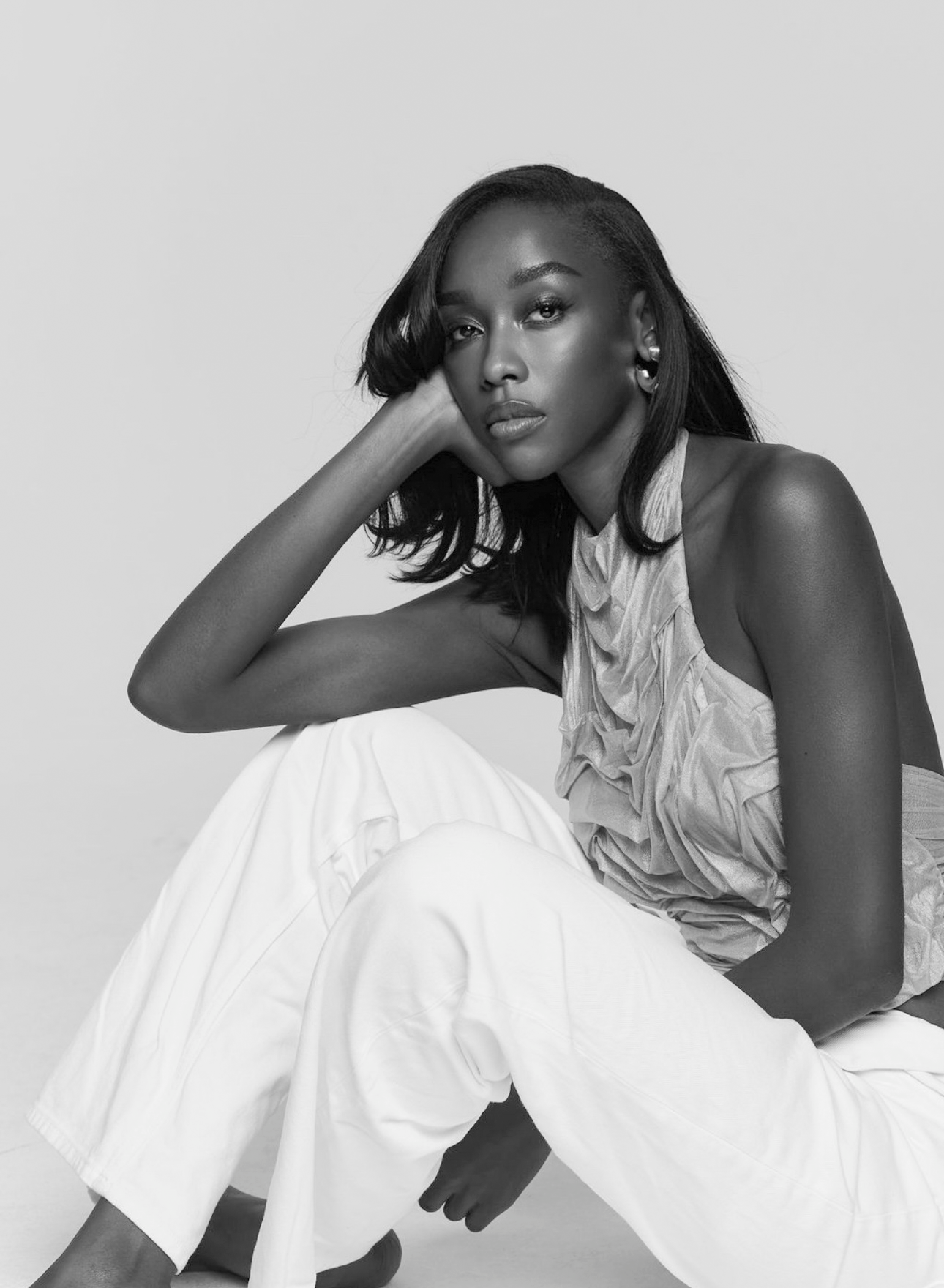Black and white photo of a woman sitting on a white background